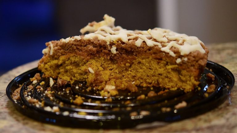 Ciasto dyniowe ucierane w jednej misce: puszysty placek z puree z dyni na Halloween i jesienne weekendy Kawałek wilgotnego ciasta dyniowego z kruszonką i polewą na talerzu